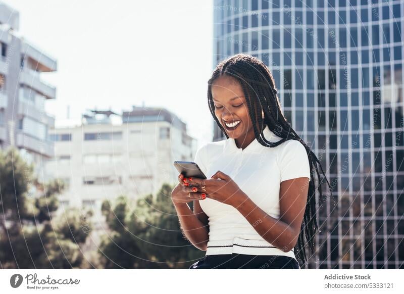 Cheerful black woman using smartphone on street cool smile browsing positive message happy surfing cellphone cheerful modern ethnic female african american