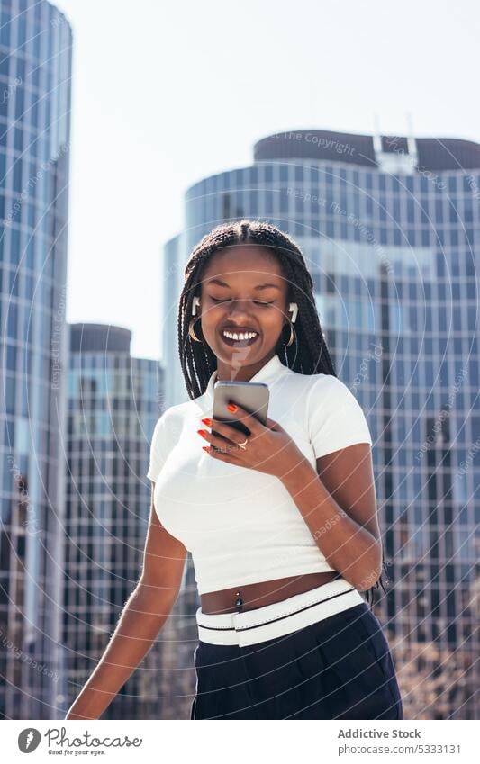 Cheerful black woman using smartphone on street cool headphones smile browsing positive music message happy surfing cellphone cheerful modern ethnic female