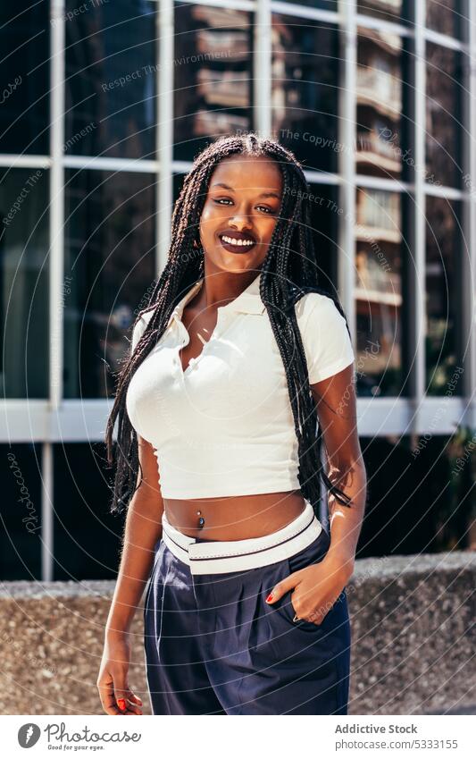Black woman with long braided hair on street portrait stare urban trendy cool gaze emotionless individuality self assured afro braids style happy ethnic female