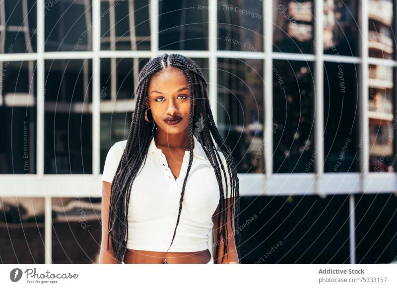 Black woman with long braided hair on street portrait stare urban trendy cool gaze emotionless individuality self assured afro braids style ethnic female young