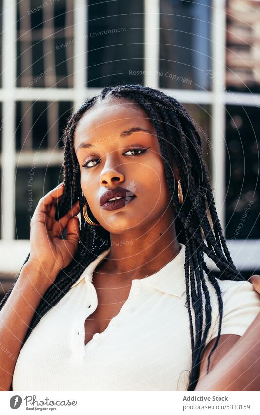 Black woman with long braided hair on street portrait stare urban trendy cool gaze emotionless individuality self assured afro braids style ethnic female young