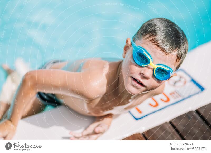 Funny kid looking at camera while leaving swimming pool boy summer vacation poolside holiday enjoy child relax rest water childhood lifestyle swimwear happy