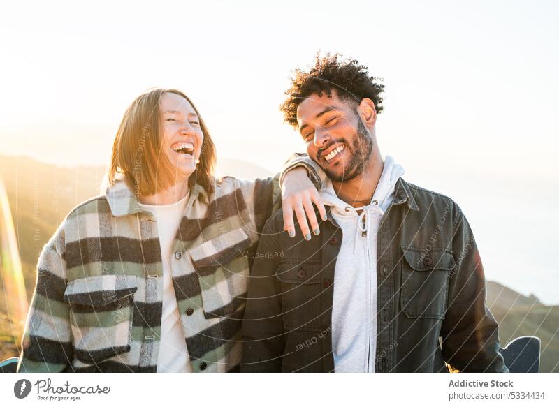 Cheerful diverse couple laughing in nature happy together cheerful sunset positive relationship love fun mountain romantic joy excited eyes closed carefree