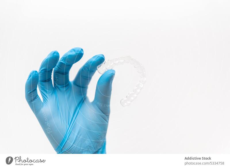 Hand with gloves holding transparent braces dentist clear aligner invisible hand dental dentistry clean doctor medical hygiene stomatology show treat white