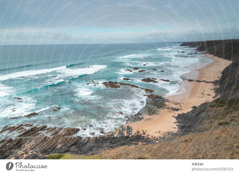 Famous Praia da Carreagem beach in the southwest of Portugal, near the town of Aljezur in the Odemira region. The waves of the Atlantic Ocean crash on the sand. Wandering the Fisherman Trail
