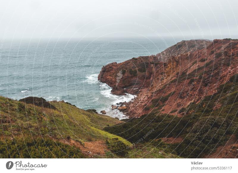 Portugal's western coastline of rocky cliffs and sandy beaches in the Odemira region. Wandering along the Fisherman trail on rainy days splash stormy weather
