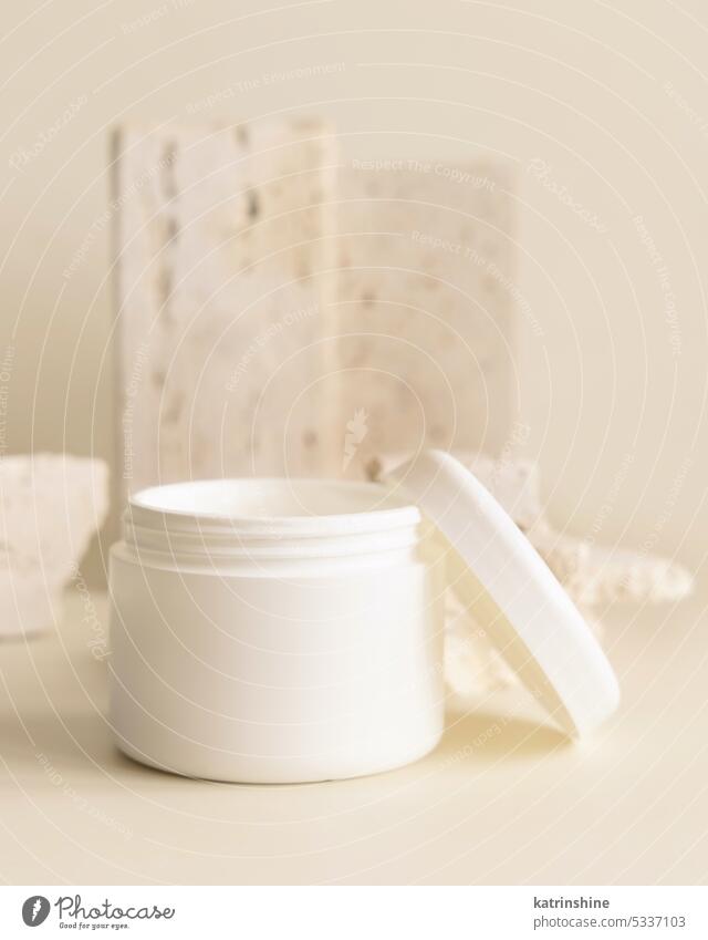 Opened white cream jar with a lid near biege stones close up. Cosmetic Mockup cosmetic mockup opened beige nature copy space Brand packaging eco frienly lotion