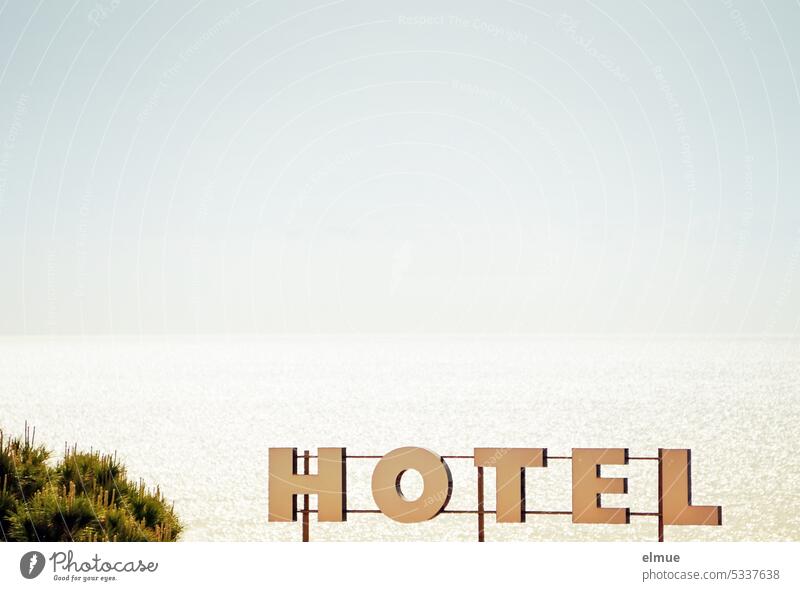 H O T E L is written in big letters in front of sea and sky Hotel beachfront overnight booking Ocean Mediterranean sea Stay Blog Accommodation dwell