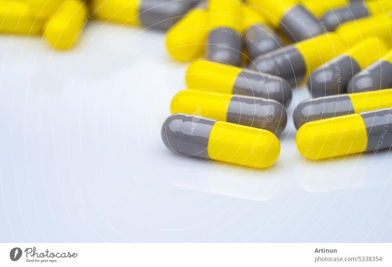 Closeup yellow and gray capsule pills on white background. Prescription drugs. Pharmaceutical industry. Health and medical care concept. Pharmacy products. Capsule pills production manufacturing.