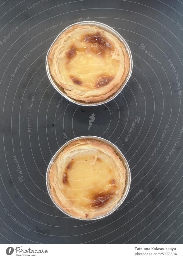 Two portuguese pasties Pastel de nata on a stone stand two Portuguese pastries dessert pastry bakery traditional custard tart sweet delicious tasty flaky creamy