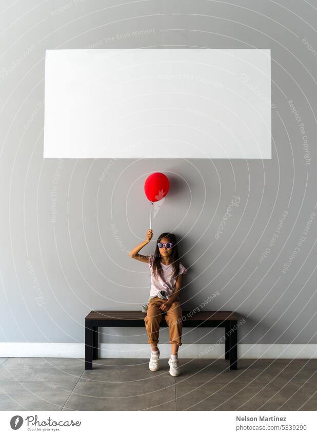 A girl sitting alone on a bench holding a globe isolated red balloon empty white board solitude contemplation reflection silence loneliness serenity thoughtful