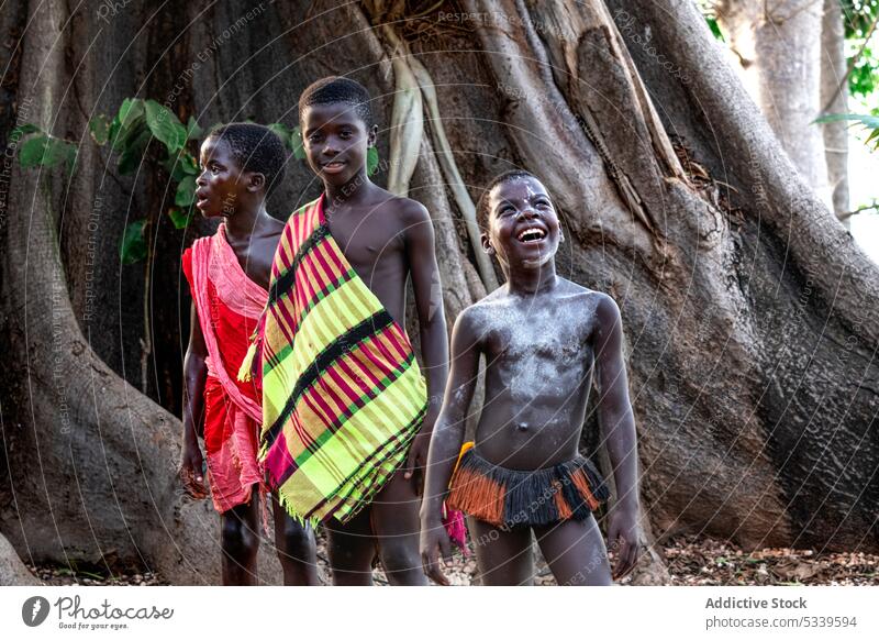 Positive tribal children standing near huge tree boy forest tribe happy nature local tradition african indigenous tropical culture environment group childhood