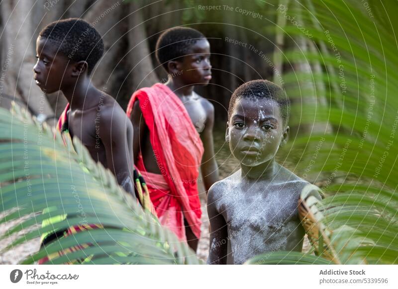 Positive tribal children standing near huge tree leafs boy forest tribe happy nature local tradition body paint african indigenous tropical culture environment