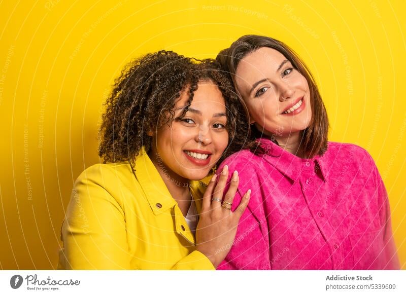 Cheerful multiethnic friends looking at camera against yellow background women girlfriend smile happy together cheerful friendship positive relationship bright