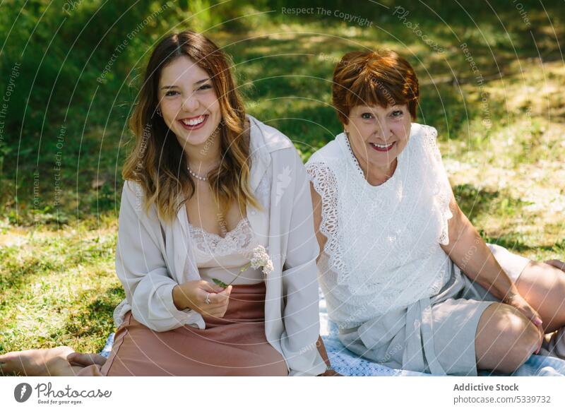 Cheerful women looking at camera and smiling on lawn granddaughter summer picnic grandmother park smile together happy rest relationship senior holiday cheerful