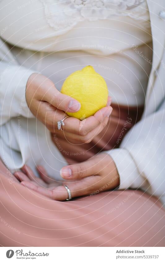 Crop woman with ripe lemon in hand accessory shirt ring fruit style silver silk vitamin yellow fresh female citrus organic natural gentle tender cloth jewelry