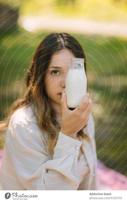 Dreamy woman drinking milk from glass bottle picnic hold nature beverage enjoy fresh female young natural tranquil long hair gentle tender calm tasty dreamy