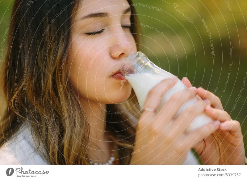 Dreamy woman drinking milk from glass bottle picnic eyes closed nature beverage enjoy fresh female young natural tranquil long hair gentle tender calm tasty