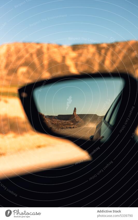 Car mirror with reflection of desert car rock mountain drive road trip formation terrain nature vehicle landscape rough rear view journey travel stone cliff