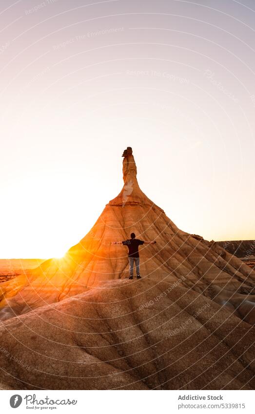 Unrecognizable traveler standing in front of rock in desert during sunset man nature admire tourist mountain sundown rocky wanderlust landscape male journey