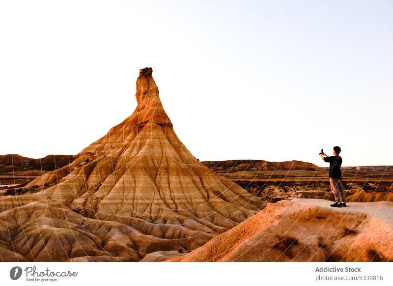 Traveler taking photo of rock formation in desert man take photo traveler tourist explore nature landscape smartphone journey male edge adventure tourism