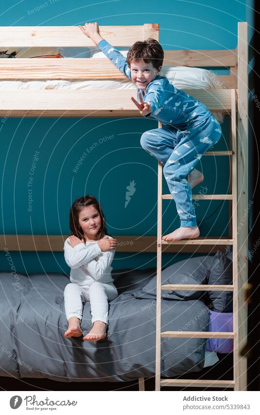 Kids playing while on bunk bed in bedroom adorable kid children bed time sibling evening wooden ladder home pajama boy girl cute little childhood brother sister