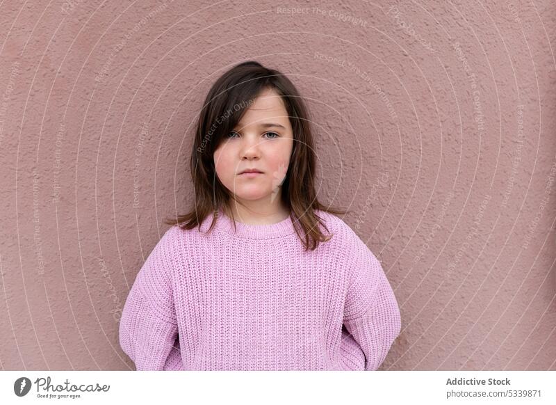 Cute child in sweater standing on pink wall and looking at camera kid adorable childhood cute preteen girl lean appearance delight charming little personality