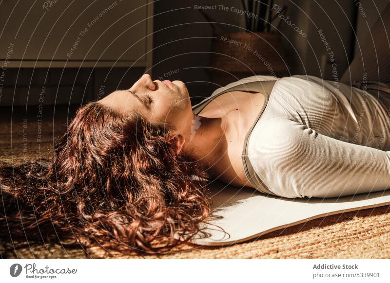 Unrecognizable woman on Shavasana pose at home corpse pose yoga practice zen mindfulness balance female meditate stress relief eyes closed stretch sportswear