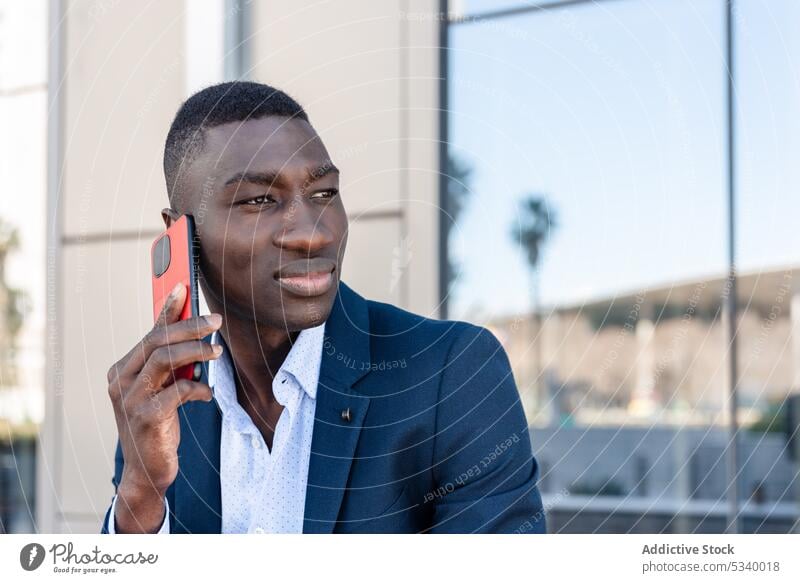Black businessman talking on smartphone near building employee speak conversation office communicate using african american male black ethnic glass mobile