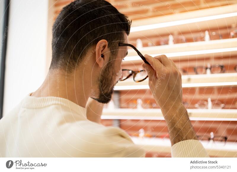 Anonymous man choosing eyeglasses in shop choose eyewear optical store customer select choice client male eyesight sale beard vision buyer option ophthalmology
