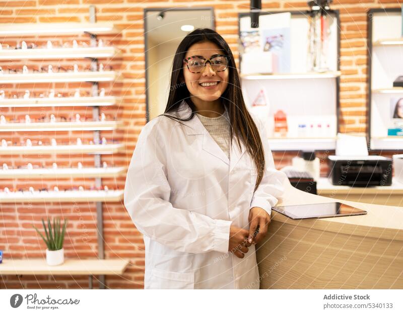 Happy female ophthalmologist in uniform and with eyeglasses looking at camera woman professional ocular optical eyewear job cheerful smile doctor positive work