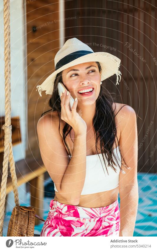 Cheerful woman talking on smartphone on swing resort smile summer conversation happy tropical female tulum mexico mexican asian young positive garden cheerful