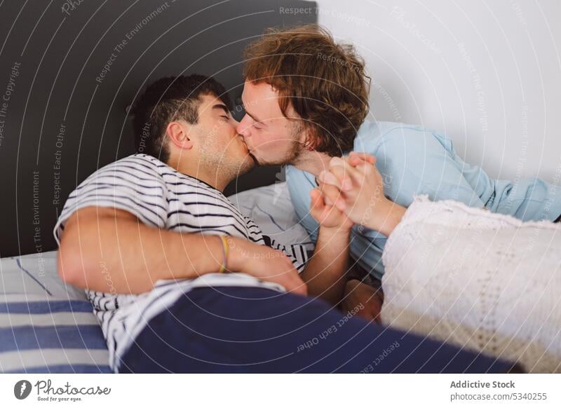 Gay couple kissing on bed men cuddle relax weekend together home lips happy love rest gay lying young smile affection relationship lgbt boyfriend homosexual