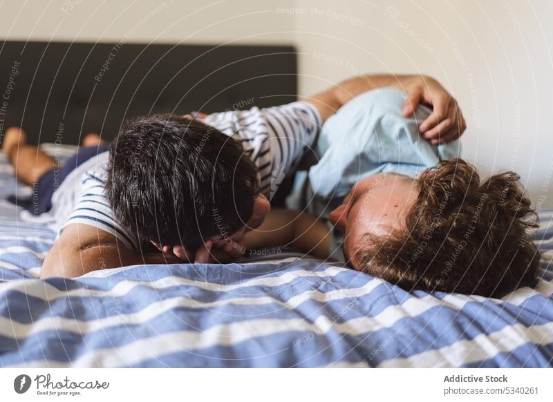 Loving gay couple kissing and hugging on bed cuddle love together relationship home affection embrace tender bonding romantic homosexual gentle boyfriend caress