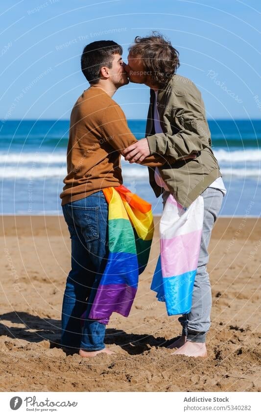 Gay couple hugging and kissing on beach men gay boyfriend transgender lgbt flag seascape male lgbtq homosexual transsexual androgynous queer equal tolerance