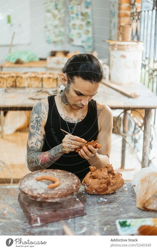 Focused potter working with clay in workshop man pottery create make concentrate workbench focus craftsman small business skill handmade ceramic creative art