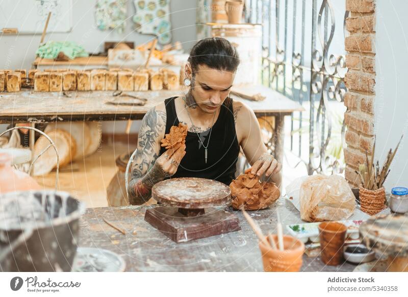 Focused man creating clay bowl on wheel in workshop pottery concentrate shape craft skill craftsman artisan ceramic focus creative handmade studio young male