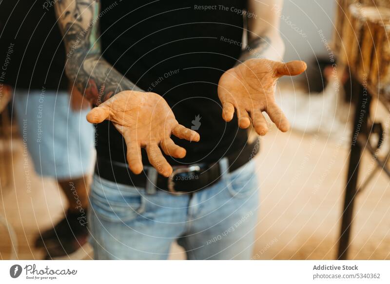 Crop tattooed man showing dirty hands in workshop demonstrate professional worker craftsman artisan male occupation skill employee service labor workplace