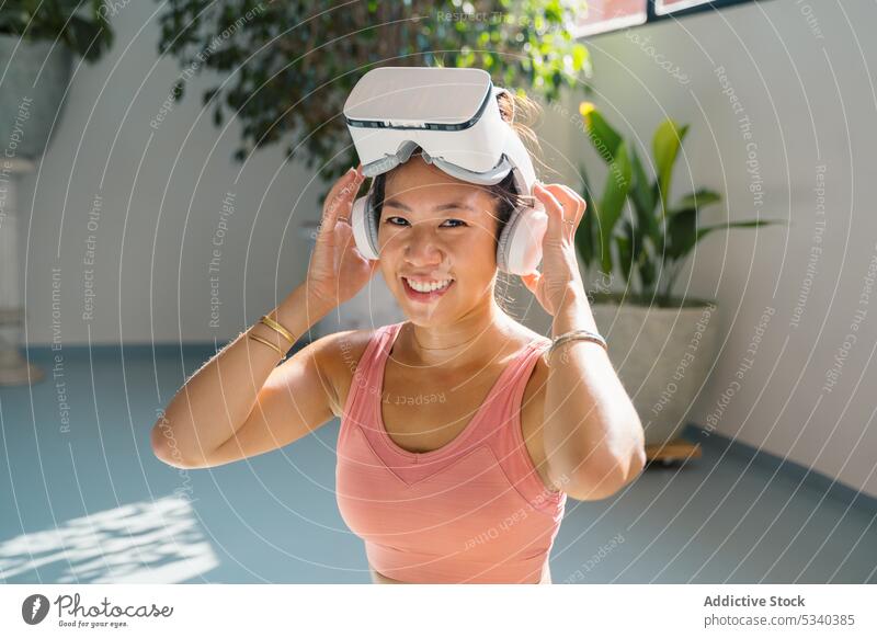 Smiling woman in VR headset on yoga mat vr smile padmasana asian chinese ethnic lotus pose virtual reality goggles cheerful practice wellness meditate
