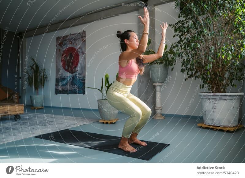 Slim Asian woman practicing Goddess pose with Cactus Arms on mat yoga asana flexible mindfulness practice concentrate goddess with cactus arms stretch female