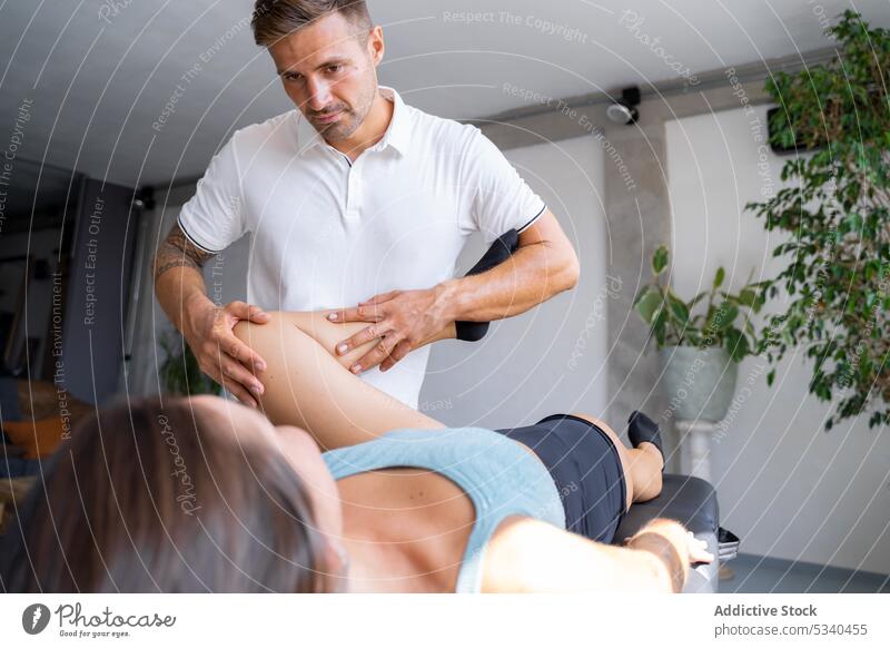 Masseur massaging leg of female client massage patient masseur therapist procedure rehabilitation treat wellness woman physiotherapist specialist physiotherapy