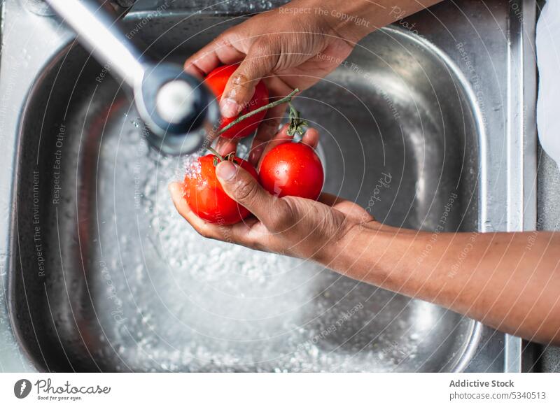 Crop man washing ripe tomatoes in sink cook chef kitchen prepare water process ingredient tap fresh vegetable clean culinary african american food faucet