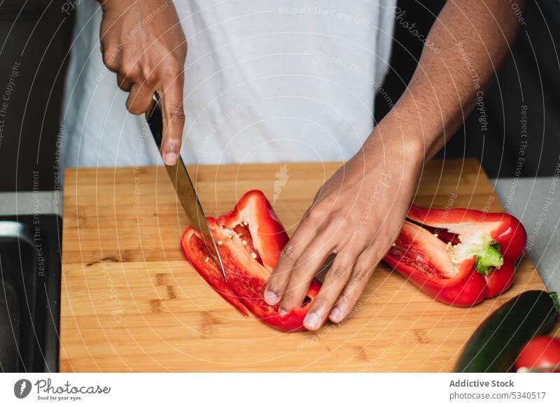 Anonymous focused man cutting bell pepper on chopping board salad knife prepare vegetable kitchen cook healthy food ripe cutting board vitamin ingredient slice