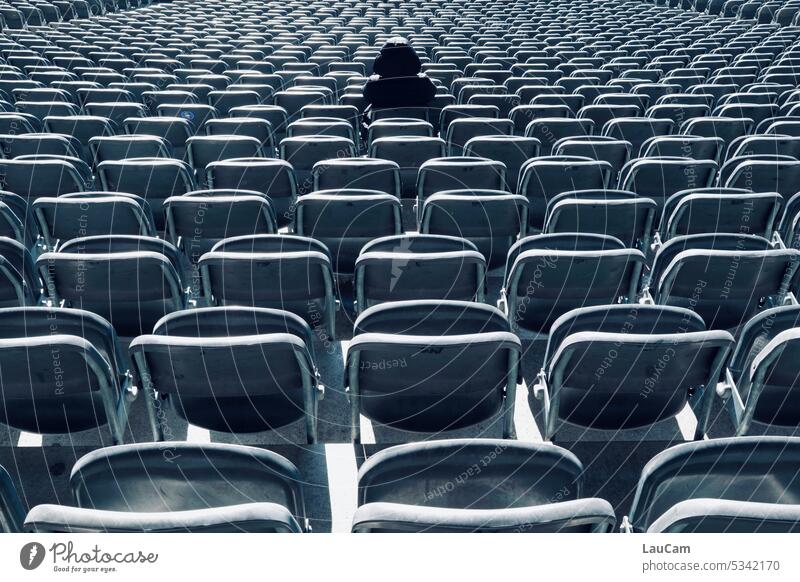 sitting - lonely figure in a sea of chairs Loneliness Lonely on one's own Doomed seats depression Empty Eerie somber Alarming Dark Creepy spectators Auditorium