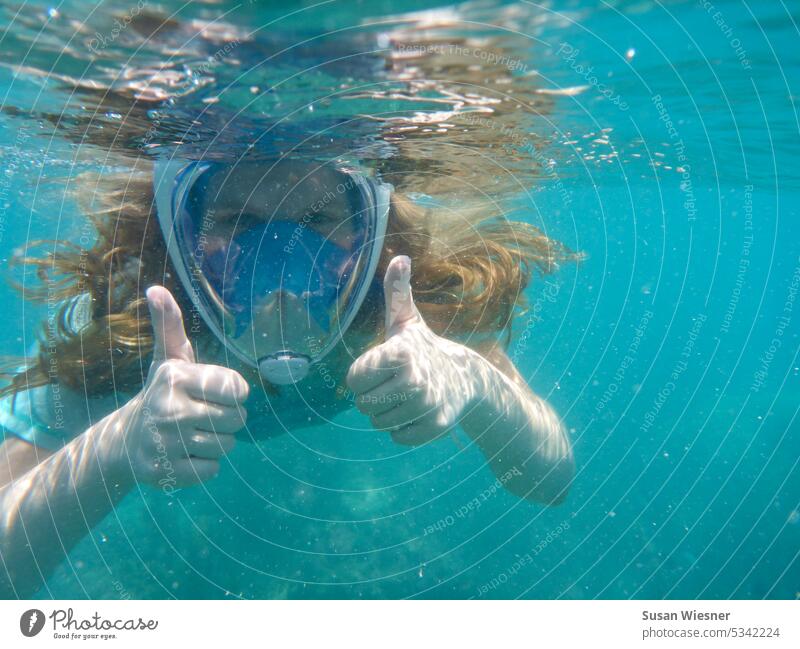 Girl with long hair and snorkel mask in turquoise water looks at camera and gives sign ok with both thumbs. Snorkeling Turquoise Water Ocean Underwater photo