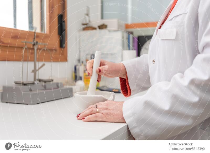 Doctor in medical uniform using mortar and pestle during medical preparation woman pharmacist prepare grind ingredient medicine process specialist equipment