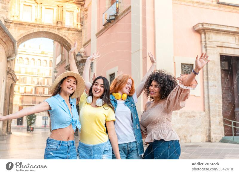 Happy diverse friends standing on street with raised hands group girlfriend celebrate building city women friendship arms raised happy cheerful multiracial