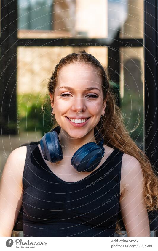 Smiling woman in headphones staring at camera happy smile listen cheerful music positive headset portrait fit female glad young wireless optimist toothy smile