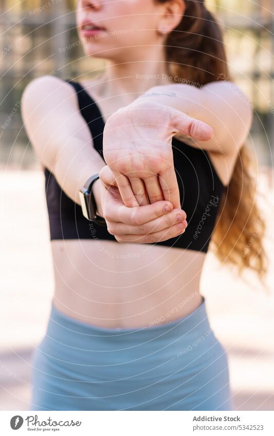 Crop sportswoman stretching arms on street fitness exercise athlete training wellbeing wellness wrist activity workout healthy smart watch vitality practice