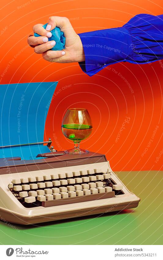 Crop woman with typewriter putting crumpled paper into glass cup colorful drink old fashioned color blocking retro inspiration style imagination vibrant concept